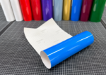 ORACAL 751C-508 Signalblau glänzende Plotterfolie, aufgerollt mit weißem Trägerpapier auf einer karierten Schneidematte