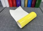 ORACAL 751C-025 Schwefelgelb glänzende Plotterfolie, aufgerollt mit weißem Trägerpapier auf einer karierten Schneidematte