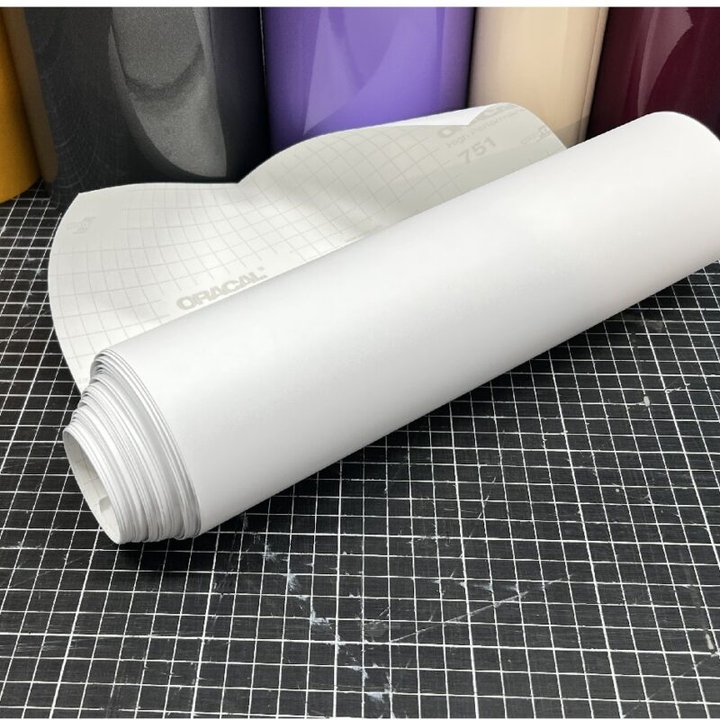 ORACAL 010 Weiß matt selbstklebende Plotterfolie, aufgerollt mit weißem Trägerpapier auf einer karierten Schneidematte