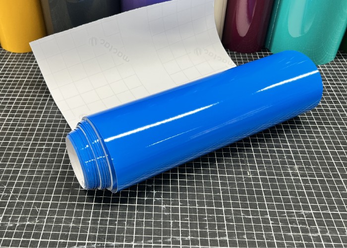 Mactac MACal 9837-00 PRO SL Luminous Blau glänzende Plotterfolie mit weißem Trägerpapier auf einer karierten Schneidematte