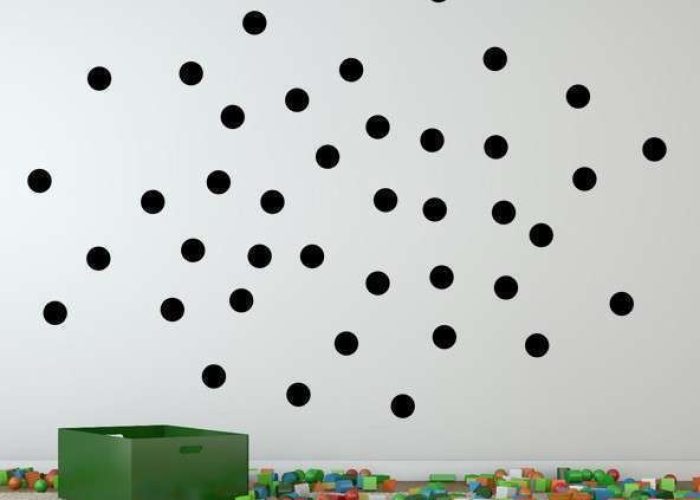 Schwarze selbstklebende Folienpunkte auf weißer Wand als Markierungspunkte und dekorative Wandgestaltung